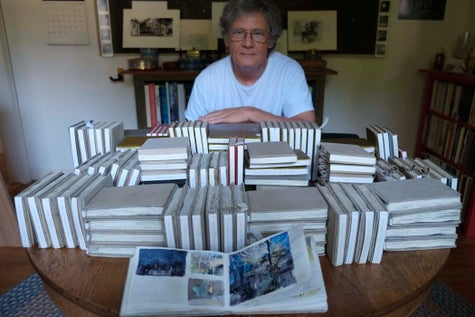 Artist Charles Ritchie photographed with the 151 sketchbook/journals he has completed since 1977
